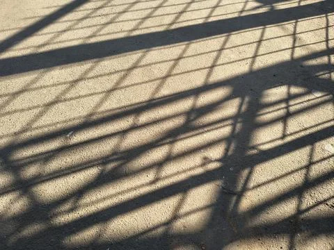 High contrast geometric grid shadow cast on textured concrete ground. Foto stock