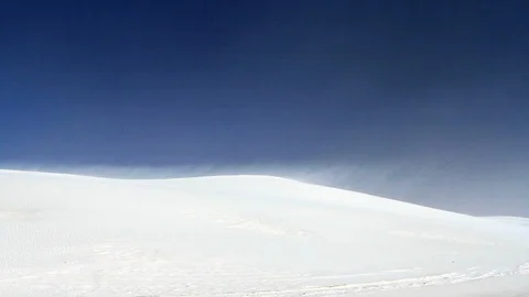 High desert winds blowing sand from the ridge of a large white dune. 動画素材 119790590