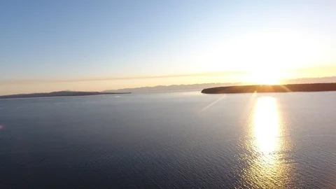 High drone shot of setting sun going behind island at sea Stock Footage 126998740