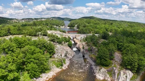 High drone view looks upstream through a rocky forest gorge toward a road Stock Footage 343801760