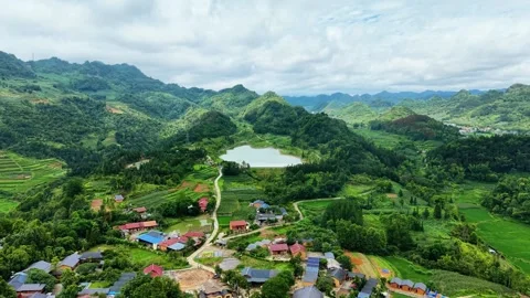 High elevation drone sweep past mountain village and natural reservoir 4K Stock Footage 341542985