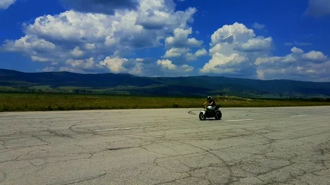 High end acrobatic biker in action training on an abandoned former air-strip Stock Footage 90008756