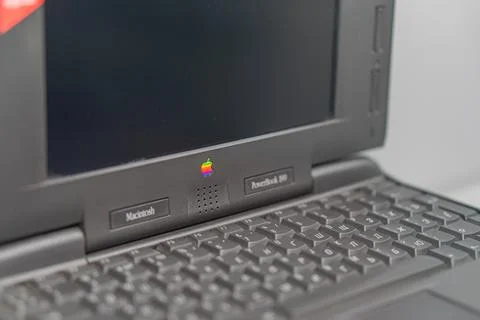High-end Apple MacBook, matte black with logo, on light surface, open screen  Stock Photos
