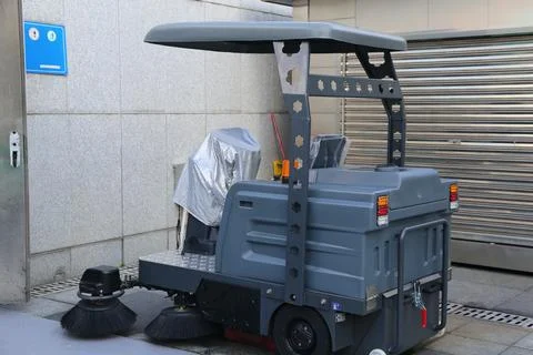 The high-end road sweeping machine is placed on the street, with a gray met.. Stock Photos