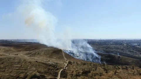 High fire in an empty field near the city. Strong smoke from burning place. Stock Footage 128111534