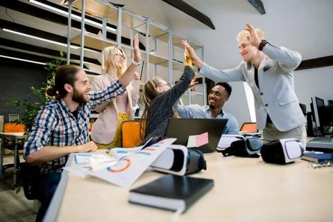 High-five for success. Diverse group of five business colleagues giving each Stock Photos