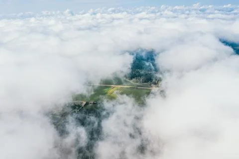 High flight in the cumulus clouds over agricultural fields in summer. Stock Photos