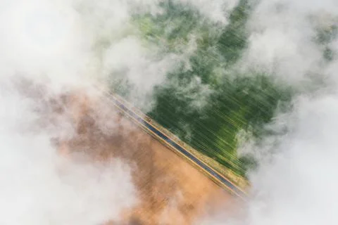 High flight in the cumulus clouds over agricultural fields in summer. Stock Photos