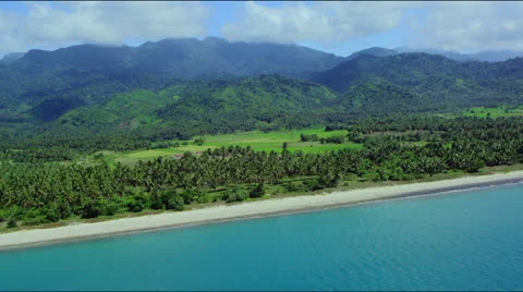 High flight over coastline with beach, green fields and mountains in the back Video stock 25332722