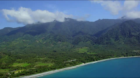 High flight over coastline with beach, green fields and mountains in the back Video stock 25333128