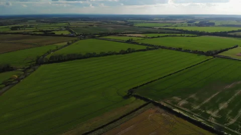 High flight over the patchwork of backlit green spring fields in Oxfordshire Stock Footage 152301270