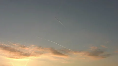 High flying distant jet  plane leaves vapour trail in sunset sky with light clou Stock Footage 57781089