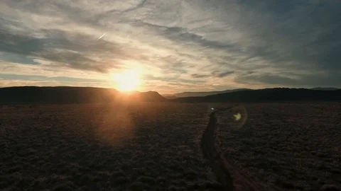 High flying drone slowly turning into desert sunset along a desert road Stock Footage 123003571
