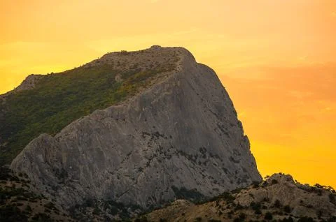 High gray mountain with a flat slope covered with greenery in orange yellow l Stock Photos