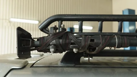 A high lift jack is strapped tightly to car roof rack Stock Footage 339685853