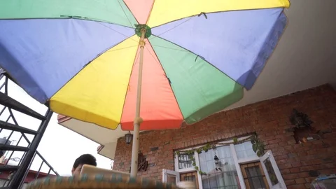 High to low shot from multi colored umbrella past table to the floor Stock Footage 91135852