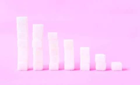 High to low stacks of sugar cubes with pink background, health care diet conc Stock Photos