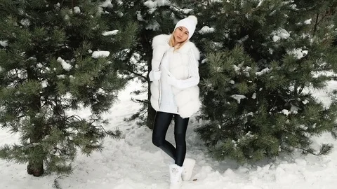 High model posing in a white dress in a green tree in the winter Video stock 70688283