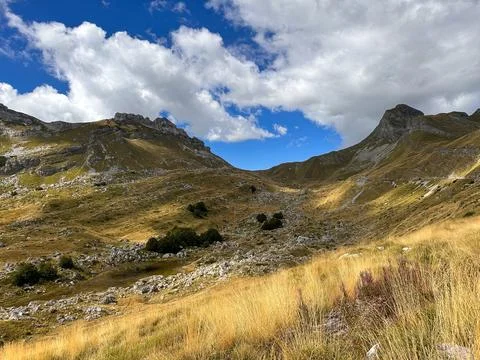 High mountain landscape with two mountain peaks, clouds, yellow shrubs and grass Stock Photos