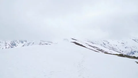 High mountain peaks covered in snow with low clouds. Trail of footprints Video stock 249048099