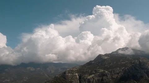 High mountain range surrounded by clouds under the bright blue sky Stock Footage 162122842