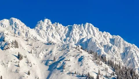 High mountain with summit cross under deep snow in winter. Rauhhorn, Allgau Stock Photos