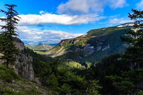 High mountains covered with dense forest, a lake in the distance. Montana, US Stock Photos