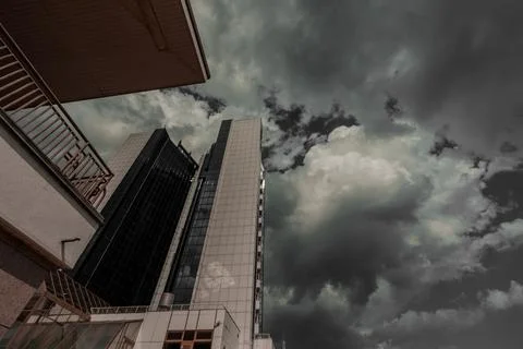 A high multi-storey building against the backdrop of a gray cloudy gloomy sky. Stock Photos