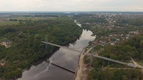 High pedestrian suspension cable bridge across the river. Urban river landscape Stock Footage 112076439