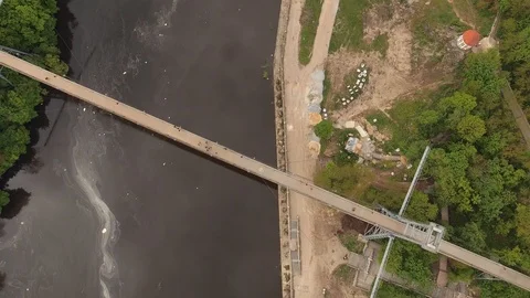 High pedestrian suspension cable bridge across the river. Urban river landscape Stock Footage 112076455