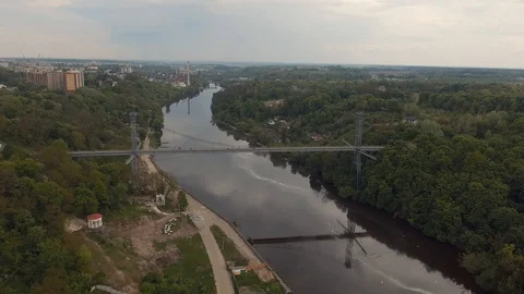 High pedestrian suspension cable bridge across the river. Urban river landscape Video stock 112076522