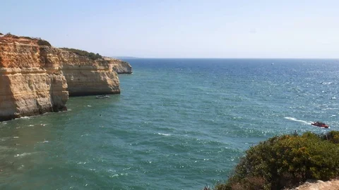 High perspective panning of gold-coloured cliffs, busy beach and turquoise ocean Video stock 115938636