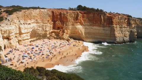 High perspective view of gold-coloured cliffs, busy beach and turquoise ocean in Stock-Footage 115938789