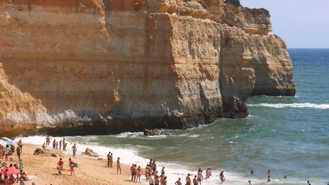 High perspective view of gold-coloured cliffs, busy beach and turquoise ocean in Stock-Footage 115939257