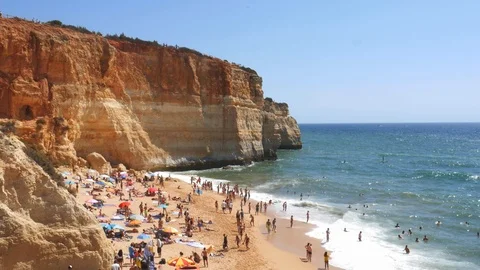 High perspective view of gold-coloured cliffs, busy beach and turquoise ocean in Stock-Footage 115939420