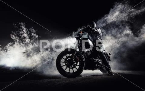 High power motorcycle chopper with man rider at night Stock Photos