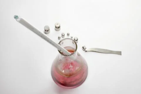 High-precision thermometer, lowered into laboratory flask with pink liquid. L Stock Photos