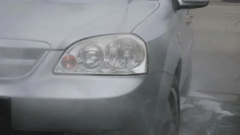 With a high-pressure cleaner, the headlight of a gray car is sprayed Video stock 160599048