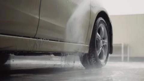 High pressure water jet removing dirt from a car surface and wheels Stock Footage 144674792