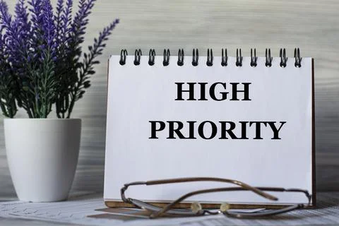 HIGH PRIORITY - words in a notebook on a light background with glasses and a Stock Photos