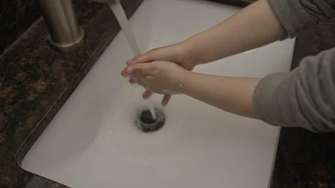 High quality close-up small boy washing his hands in a granite sink. Stock-Fotos