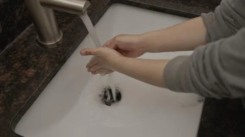 High quality close-up small boy washing his hands in a granite sink. Stock Photos