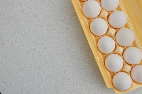 High quality white eggs packed in a yellow carton, ready for culinary use. 库存照片