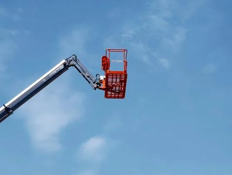 High-reaching cherry picker working against a clear blue sky during daylight Stock Photos