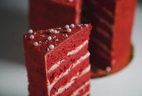 High red cake stands on a white table and piece of cake. Stock Photos