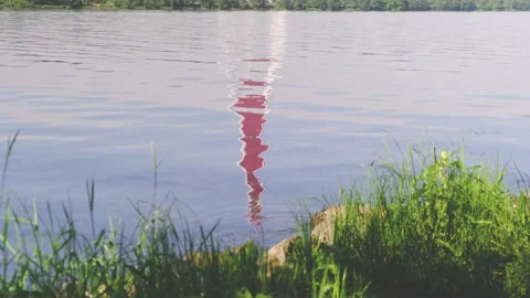 High red lighthouse reflects in still blue river water Stock Footage 136420711