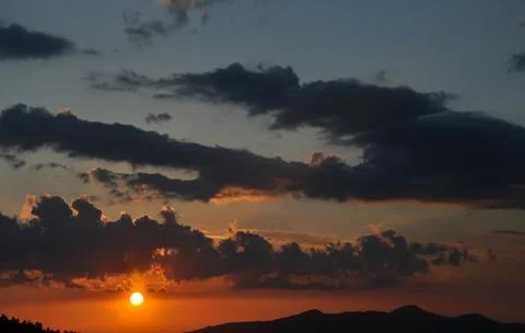 High resolution shot of sun with clouds during sunset of hilly area Stock Photos