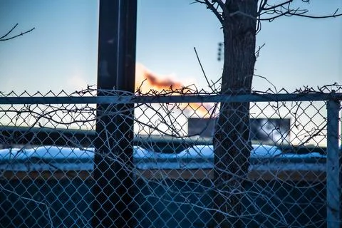 High-resolution shot of sunset city smog through chain link fence Stock Photos