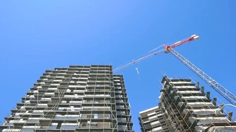 High-rise building construction site with cranes against blue sky Stock Footage 76961304