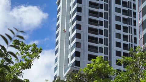 High Rise Building Painter Working at Extreme Height on Tower Exterior 库存影片 343698105